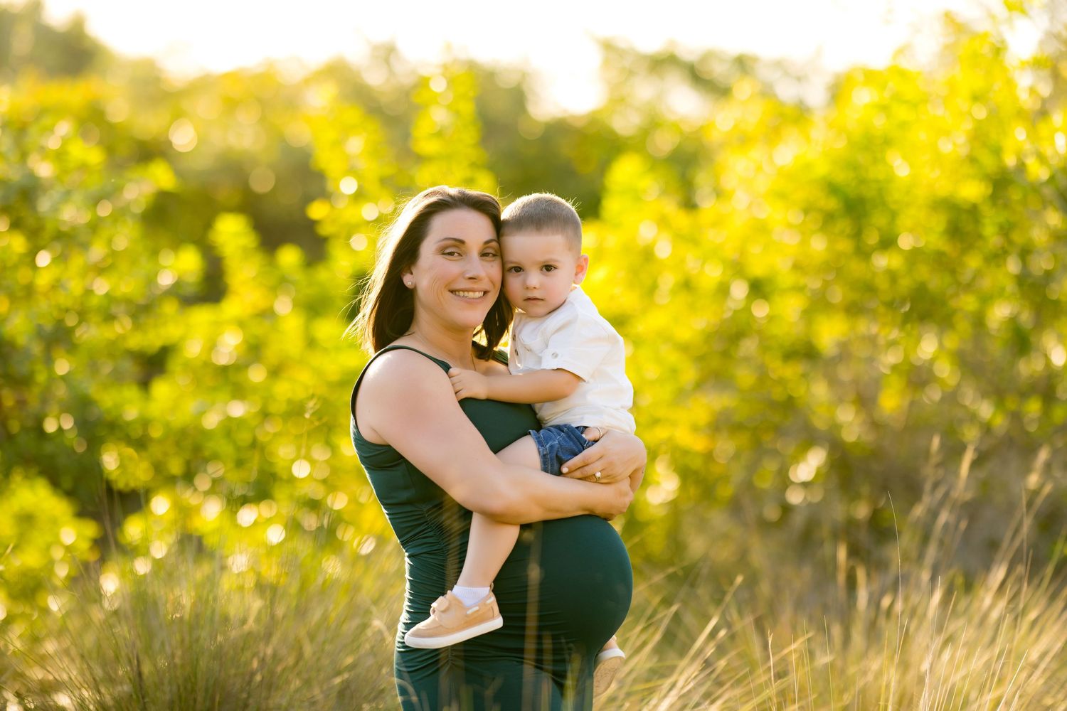 Joyful family embracing in a sunlit field with golden late afternoon light.