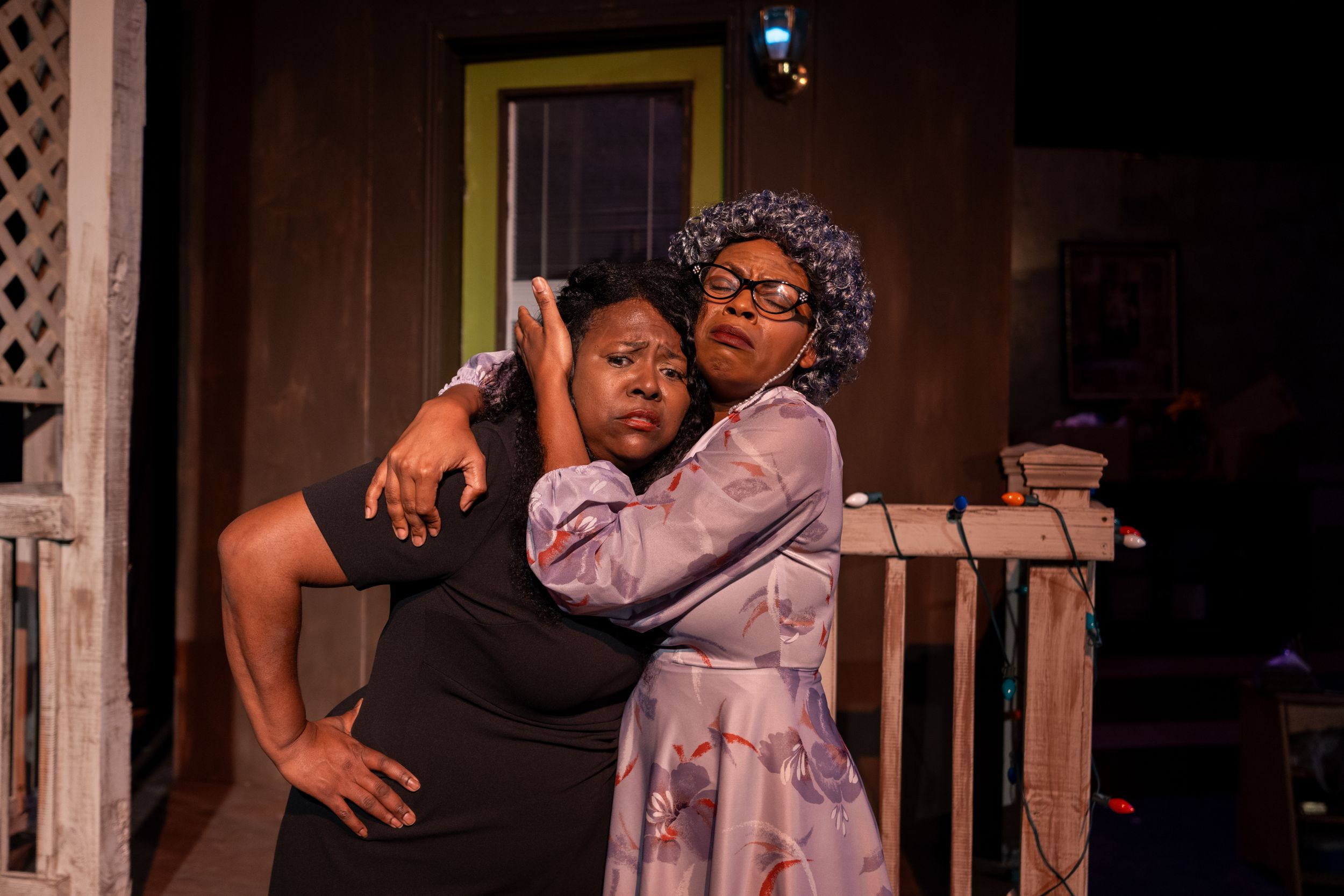 Two performers act out an emotional scene on stage with dramatic lighting.