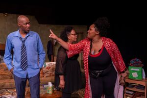 Three actors perform an emotional scene in a theatrical play with dramatic expressions and gestures.