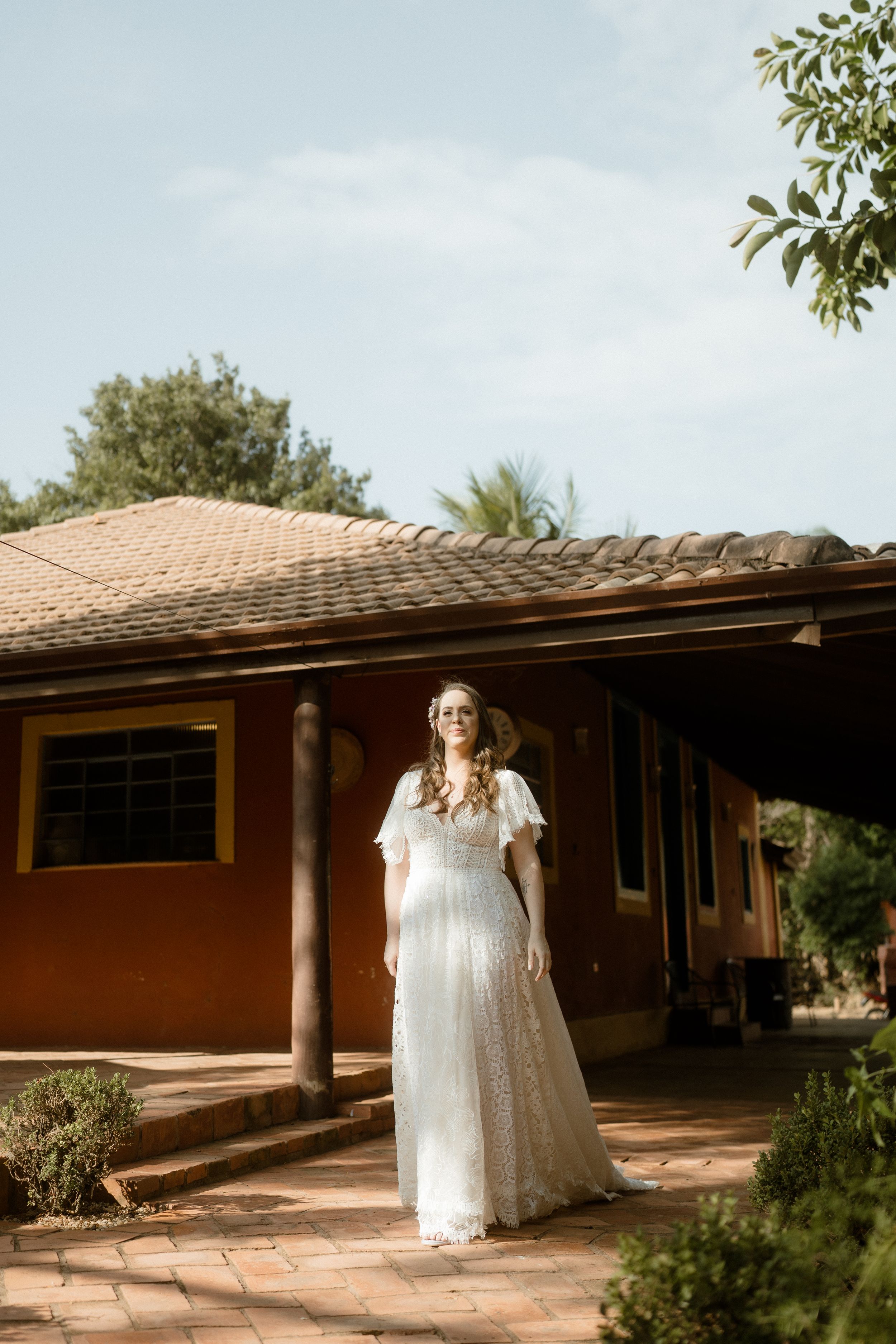 Lace wedding dress silhouette against terra cotta house with tiled roof.