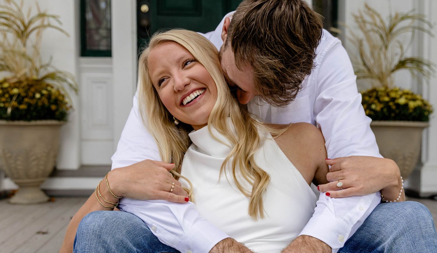 Casual couple in white shirts sharing tender moments on a porch.