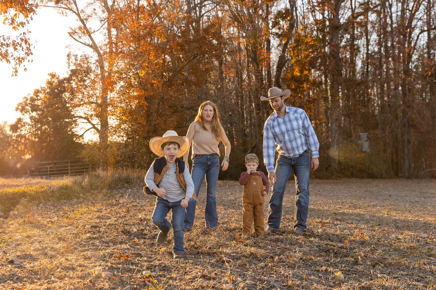 Family group walking together in autumn forest setting during golden hour.