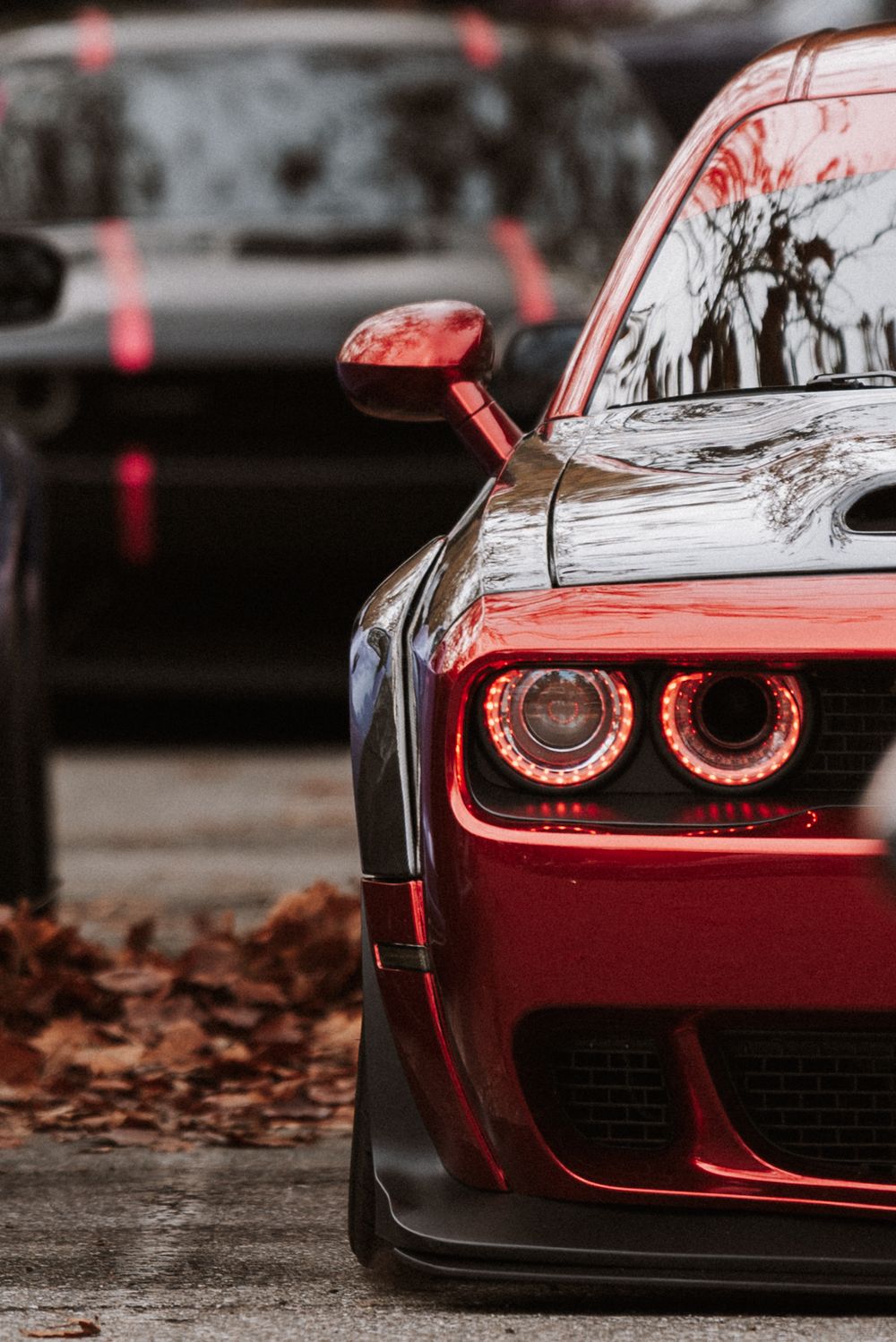 Close-up shots of a red Dodge Challenger's headlights and front end details showing glowing red LED rings.