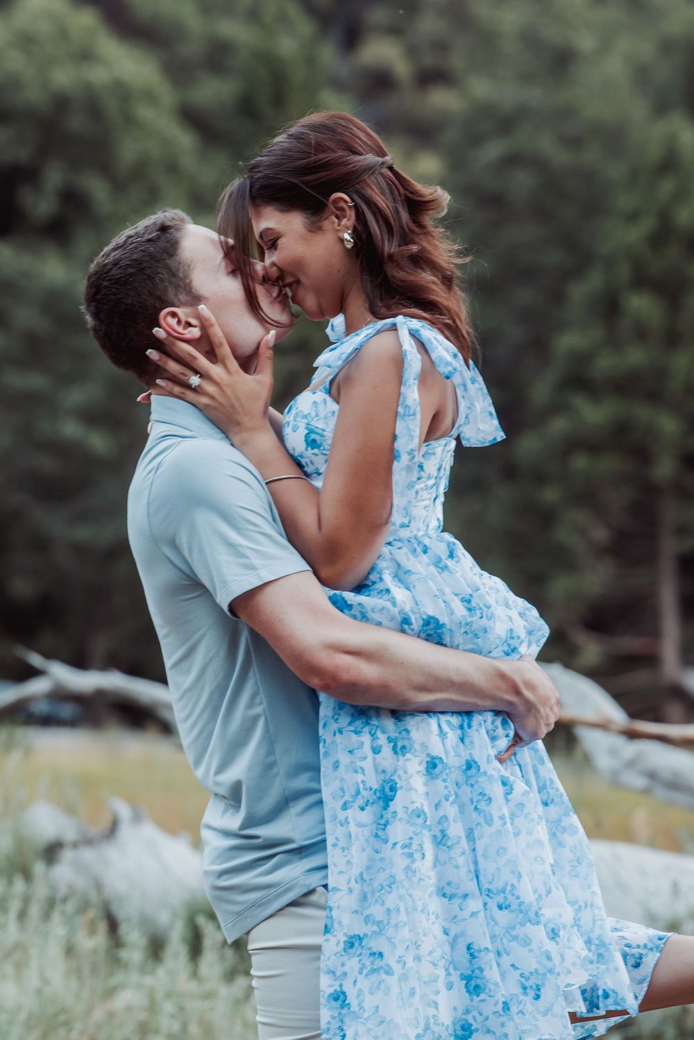 A couple embraces outdoors in coordinating blue and grey outfits during a romantic photoshoot in nature.