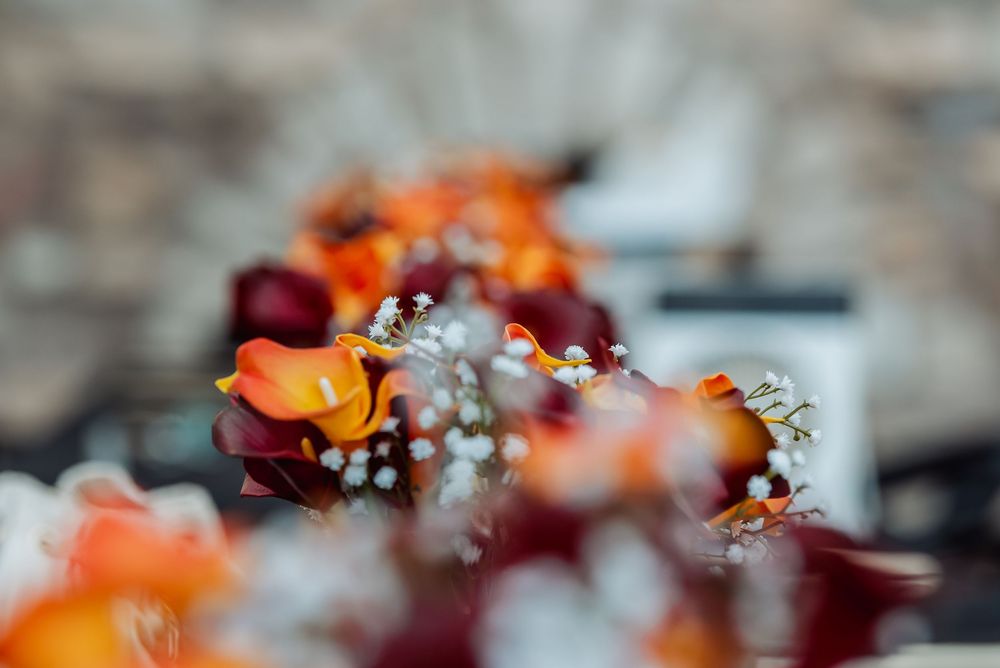 Close-up detail of orange and burgundy floral arrangements with baby's breath accents during an Elk Grove, CA wedding.