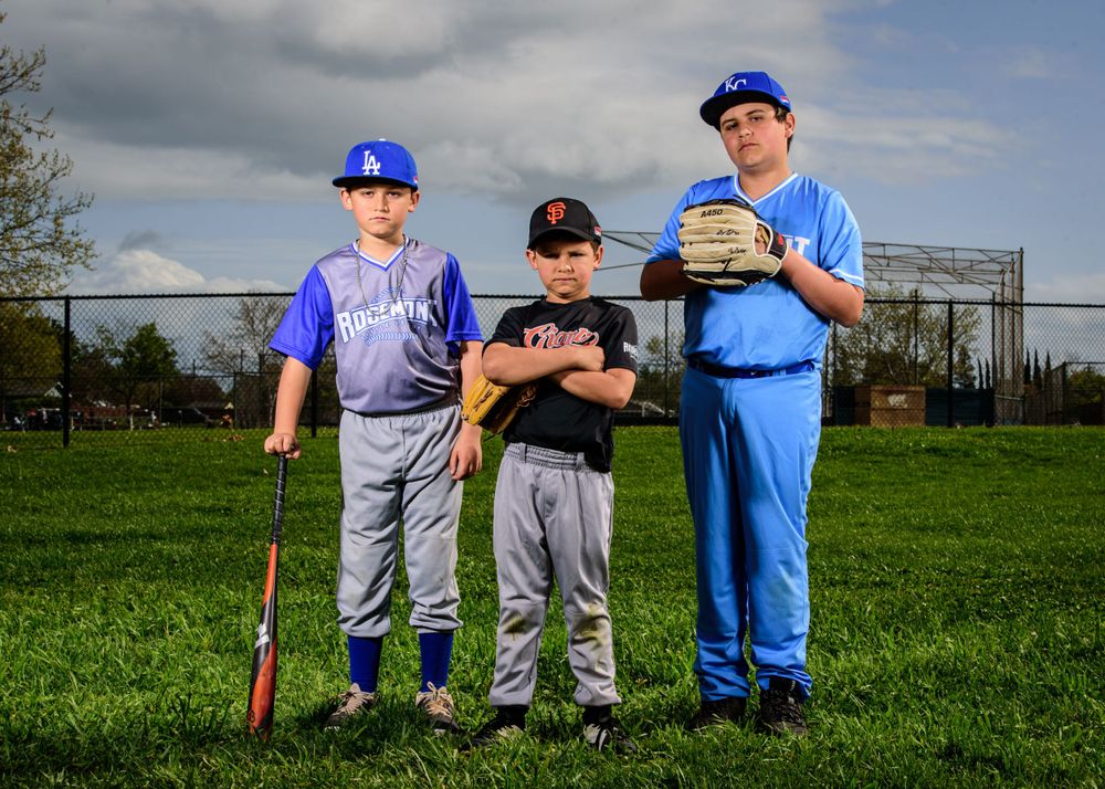 Baseball players in uniform gather on a green field under cloudy skies for dynamic portraits.