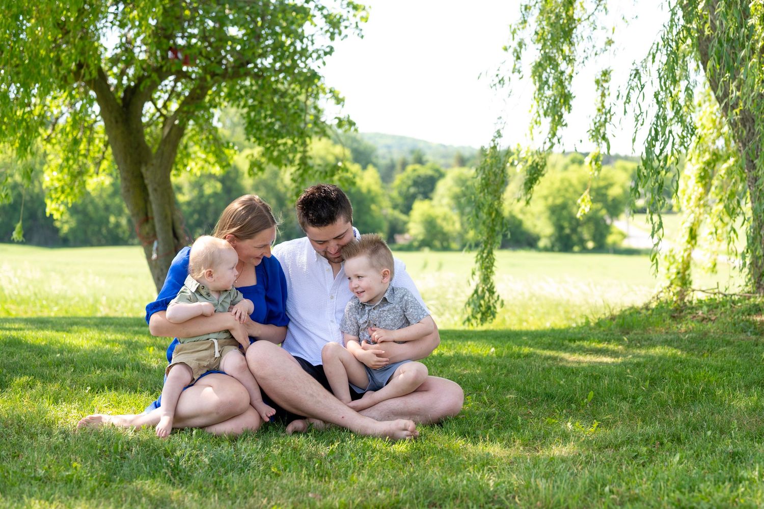 A family stands together in a sunlit meadow during a summer evening photo session.