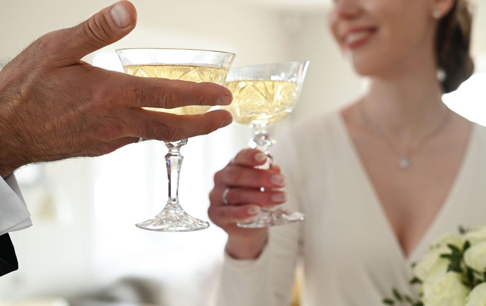 Two people toasting with champagne coupe glasses at an elegant celebration.