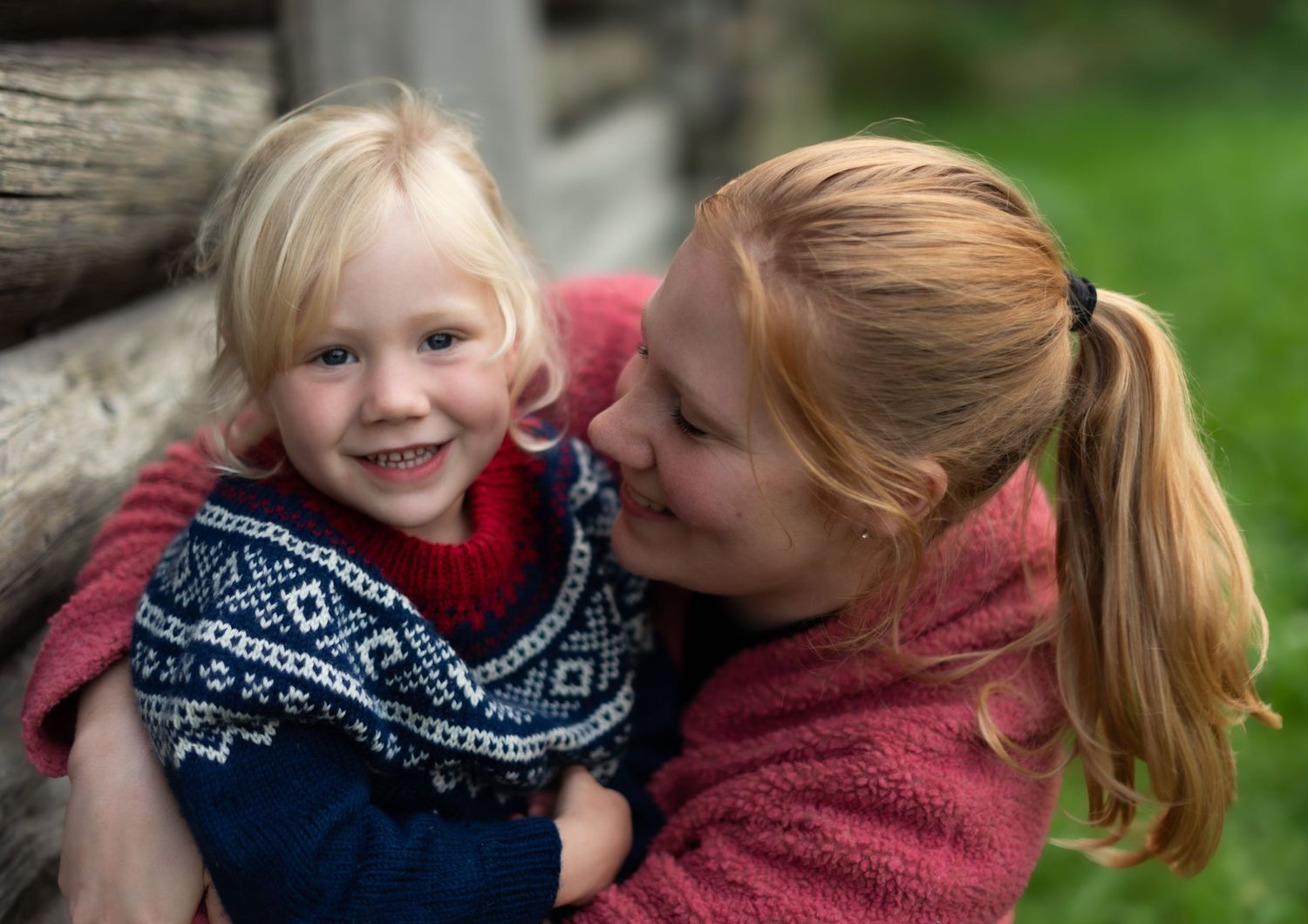 Two people sharing a warm embrace while wearing matching winter sweaters outdoors.