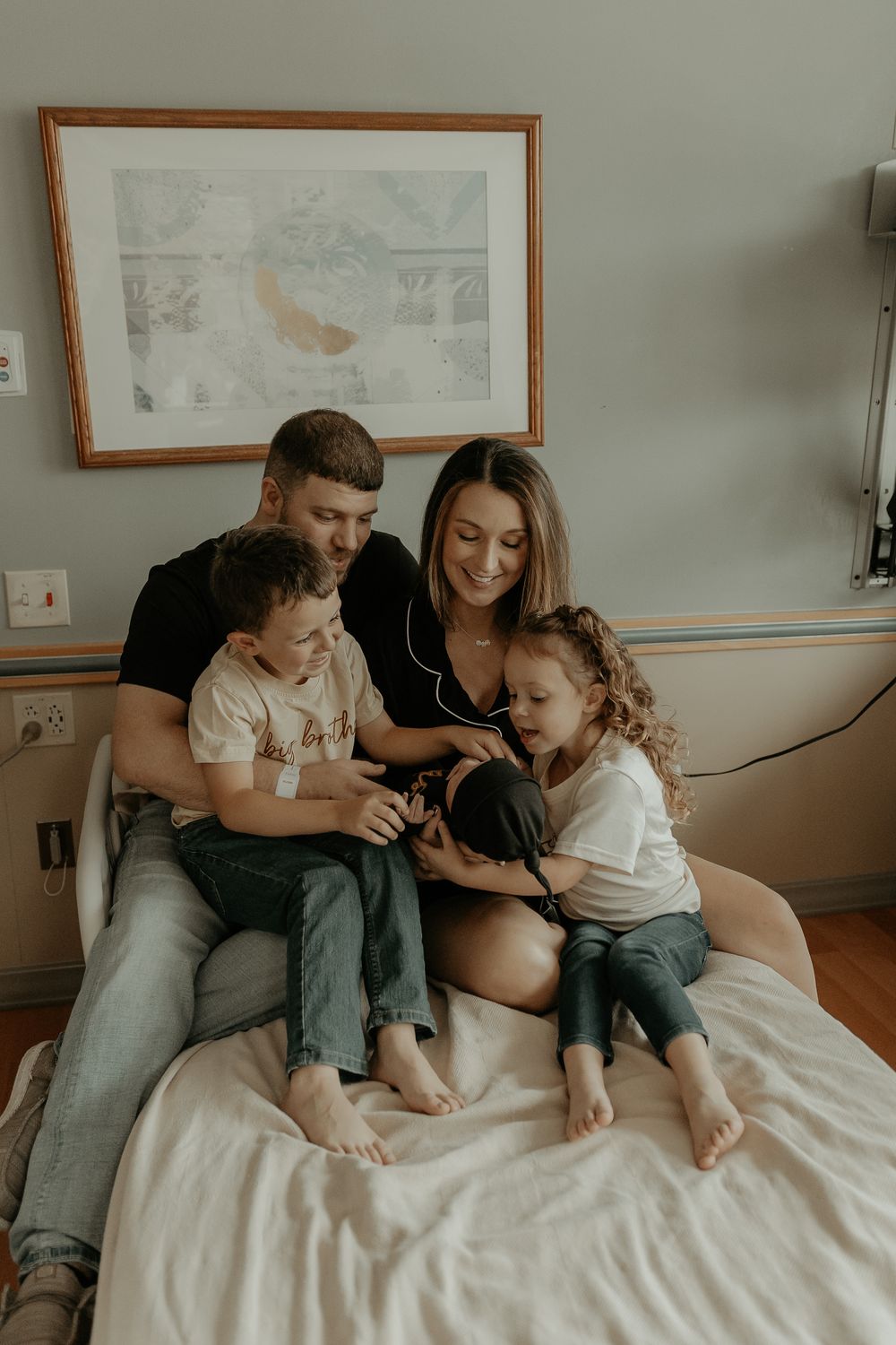 A family relaxes together on a hospital bed while bonding with their new baby.