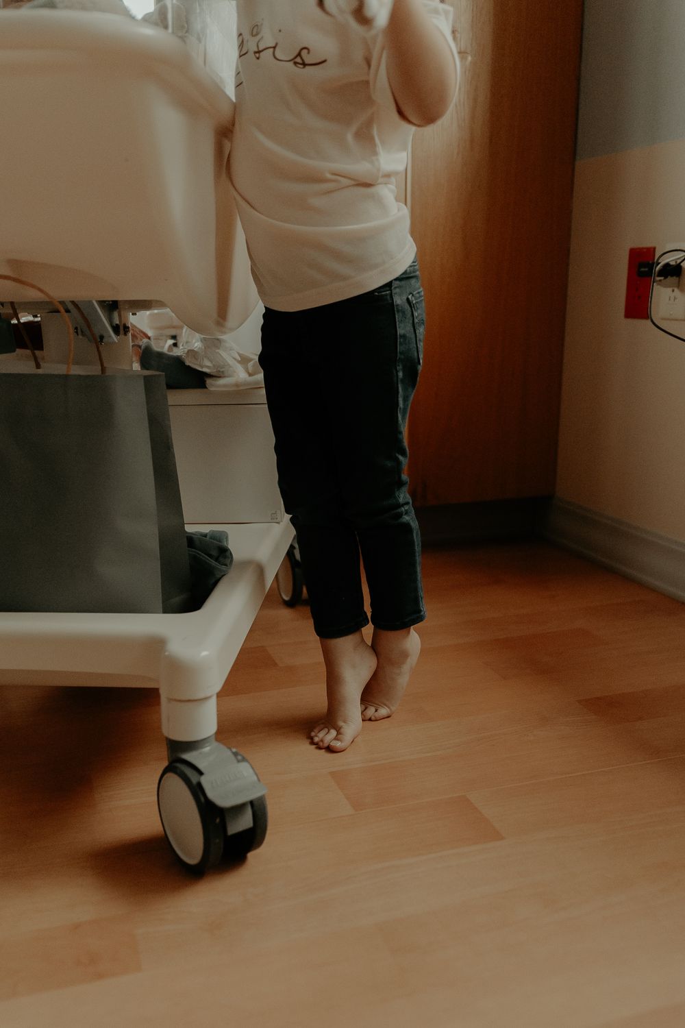 Close-up view of feet and legs walking with a hospital bassinet.
