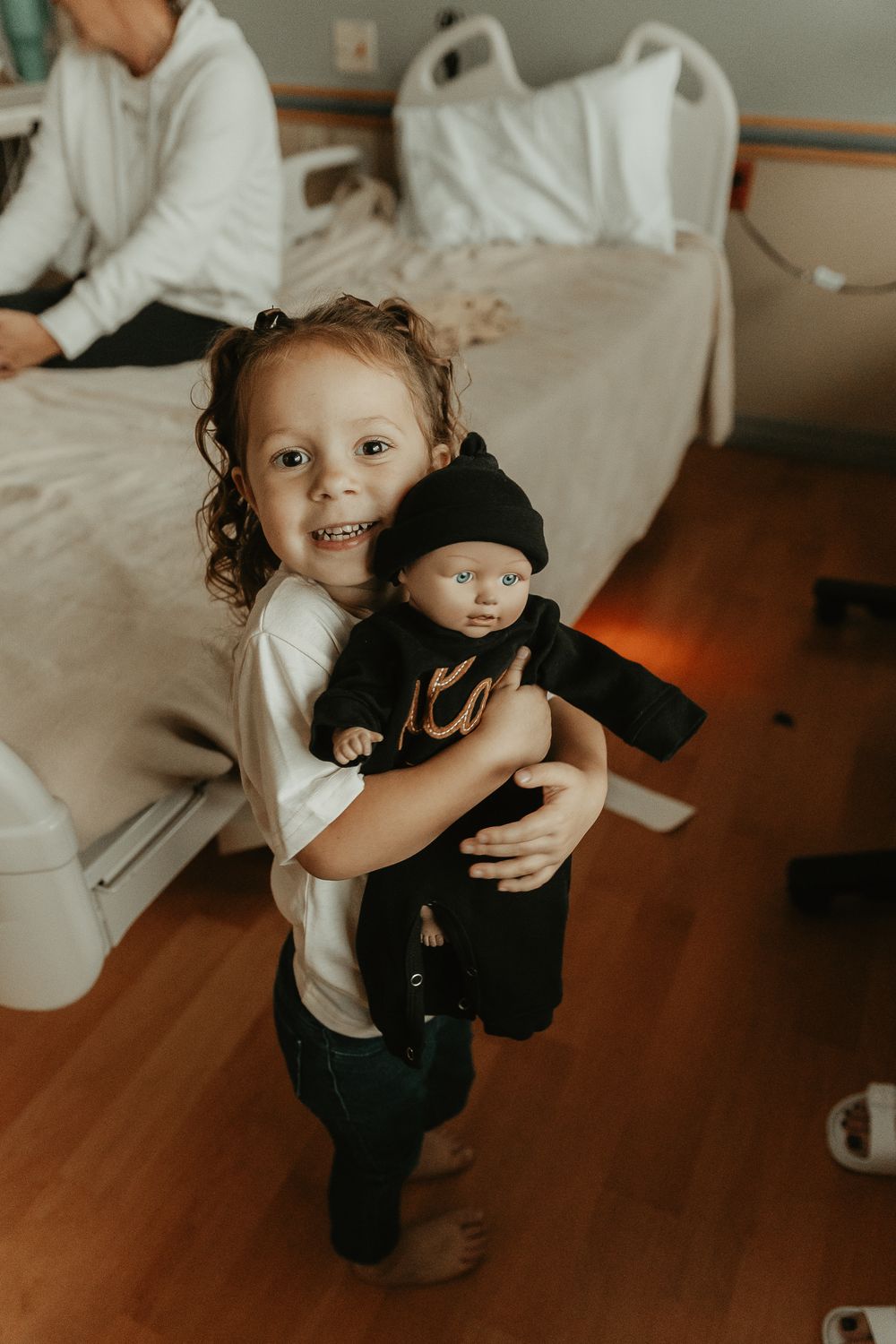 A small child holds and hugs a black stuffed animal toy.