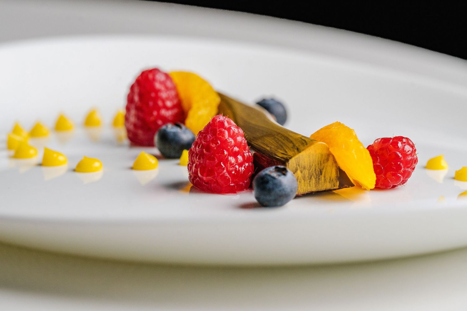 Fresh raspberries, blueberries, and mango pieces are artfully arranged by culinary students.