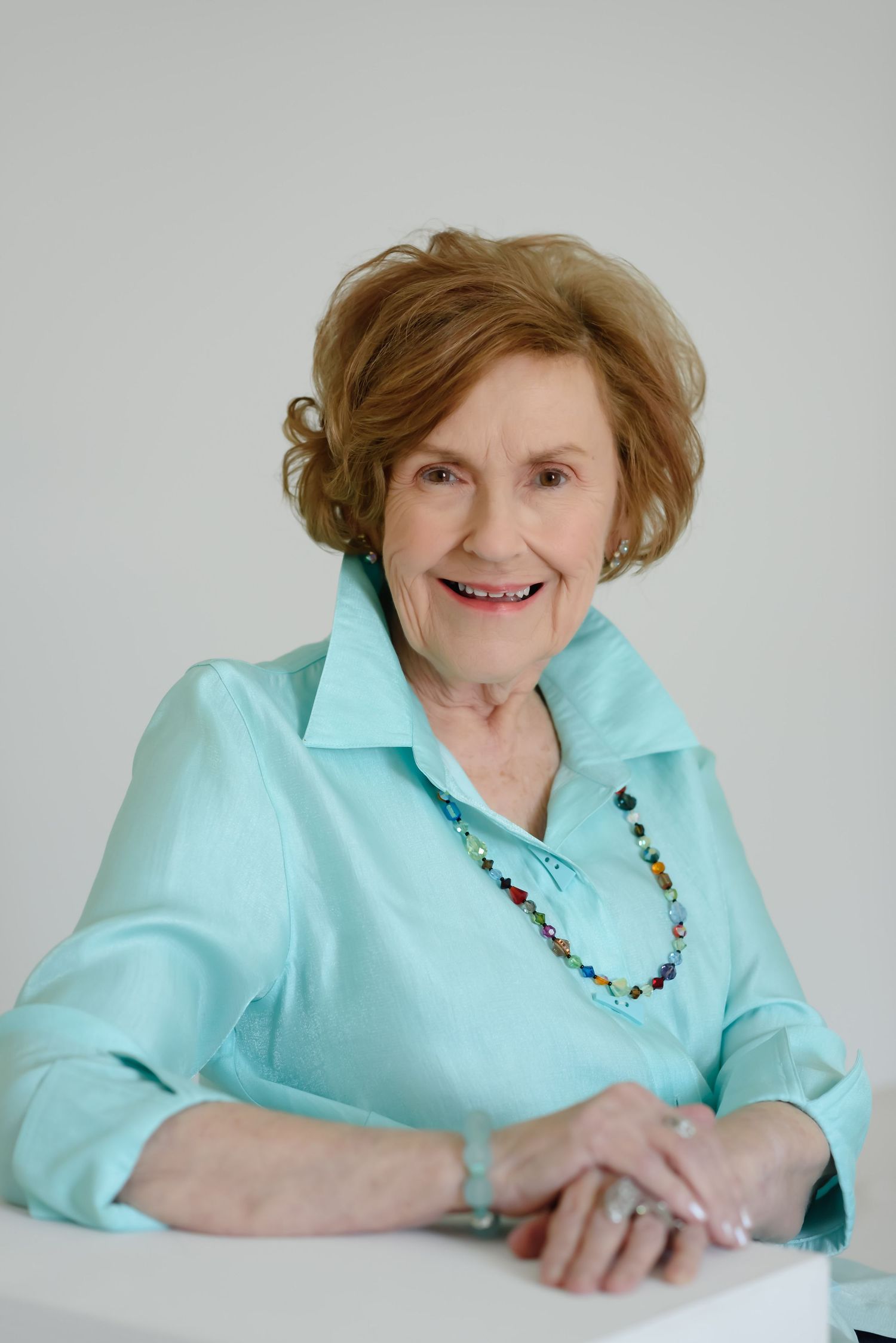 mature woman smiling wearing glasses in green by connie shuffett photography studio