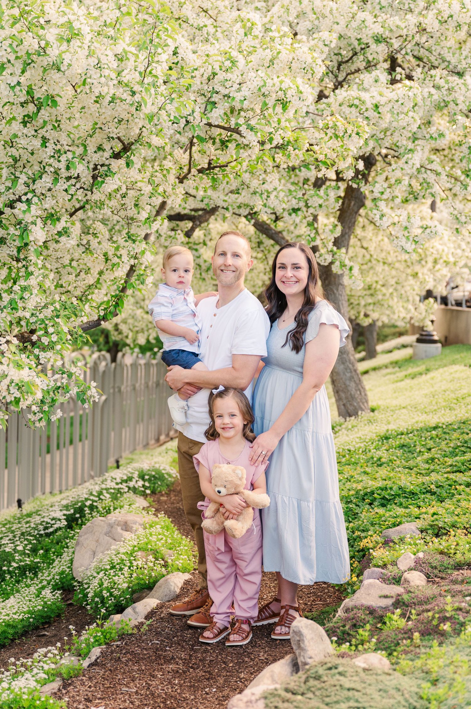 Family portrait under blooming spring tree with white flowers.