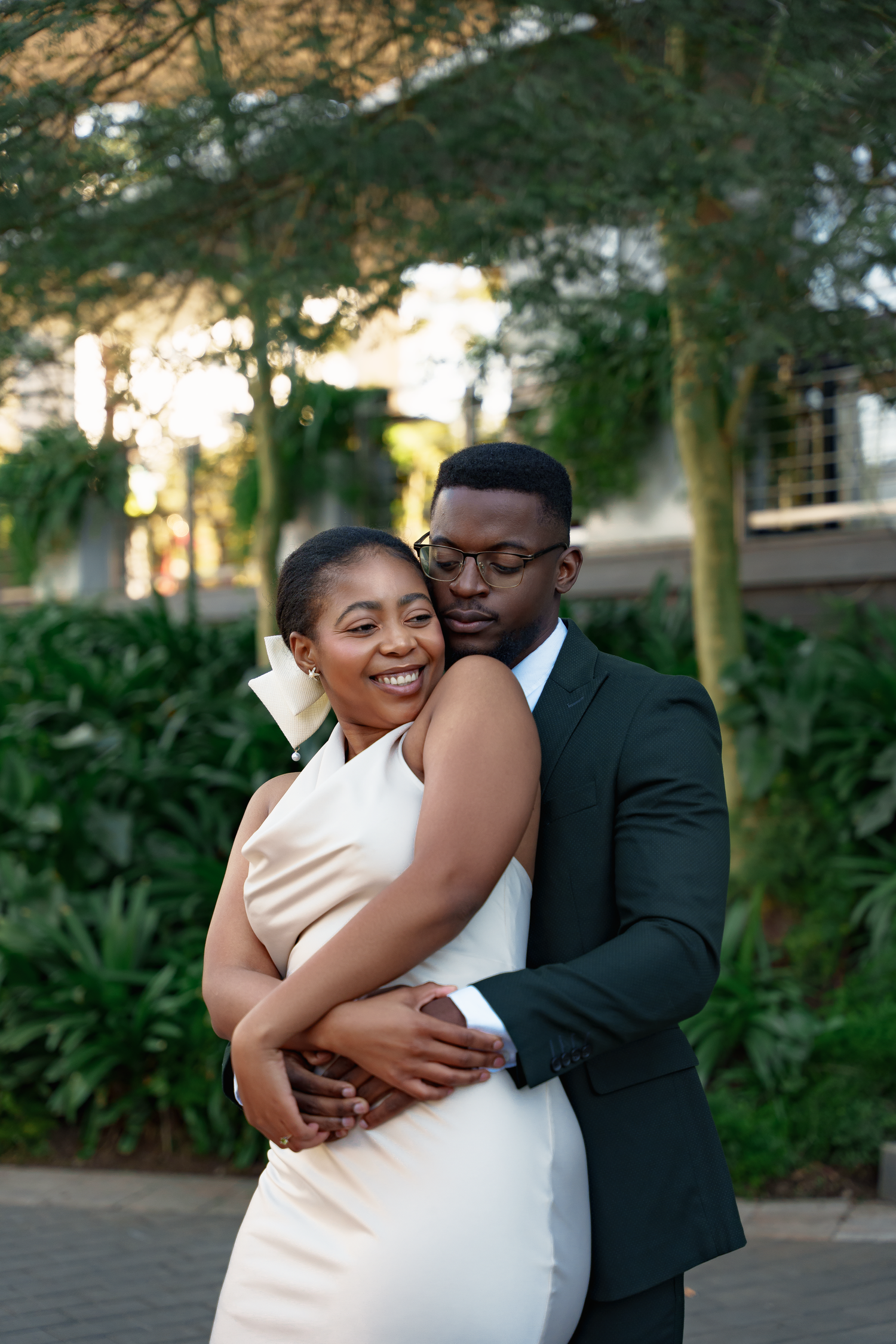 Happy couple embracing outdoors in wedding attire during sunset.