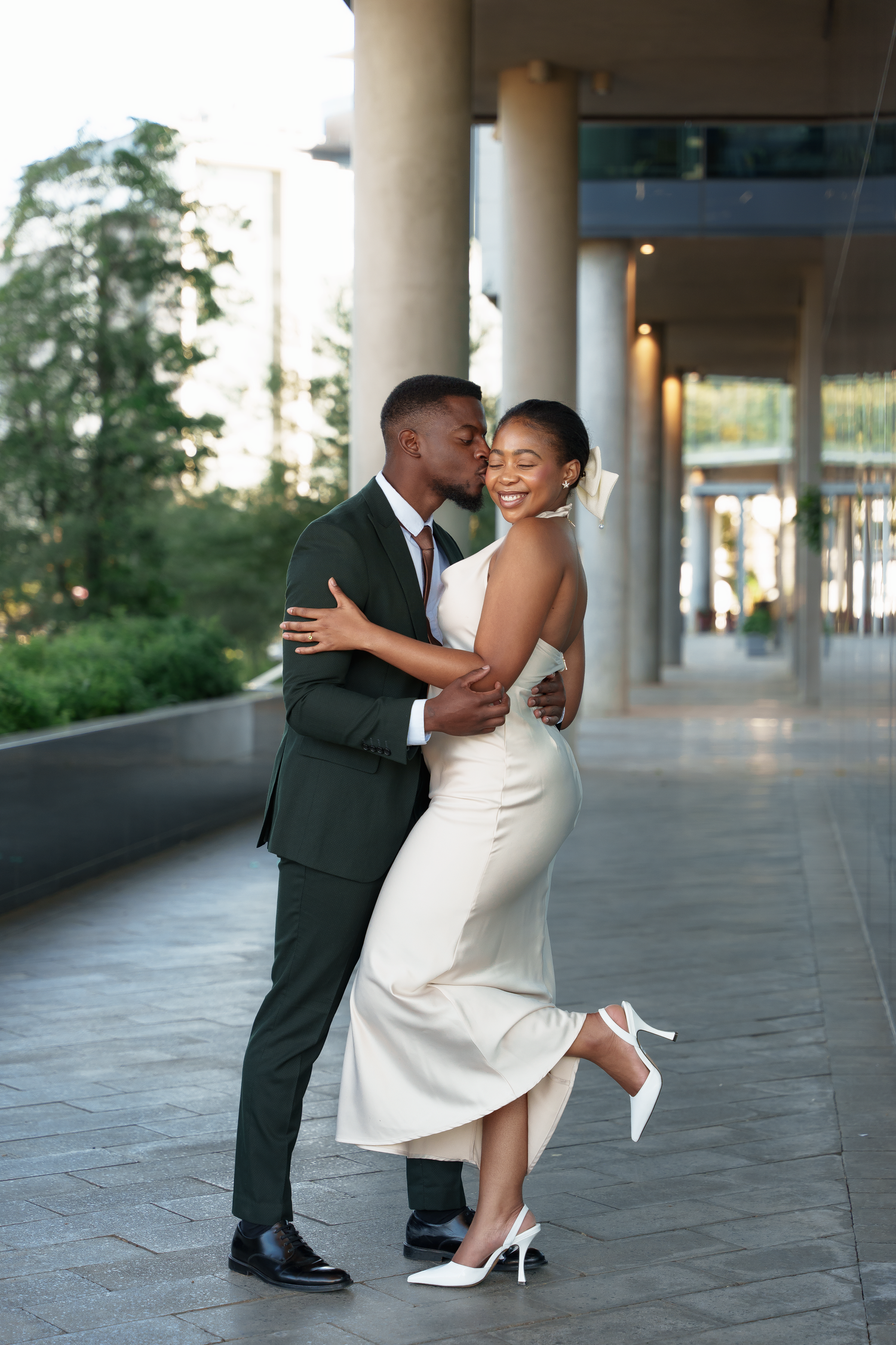 Couple in formal attire dancing and embracing in modern building hallway.