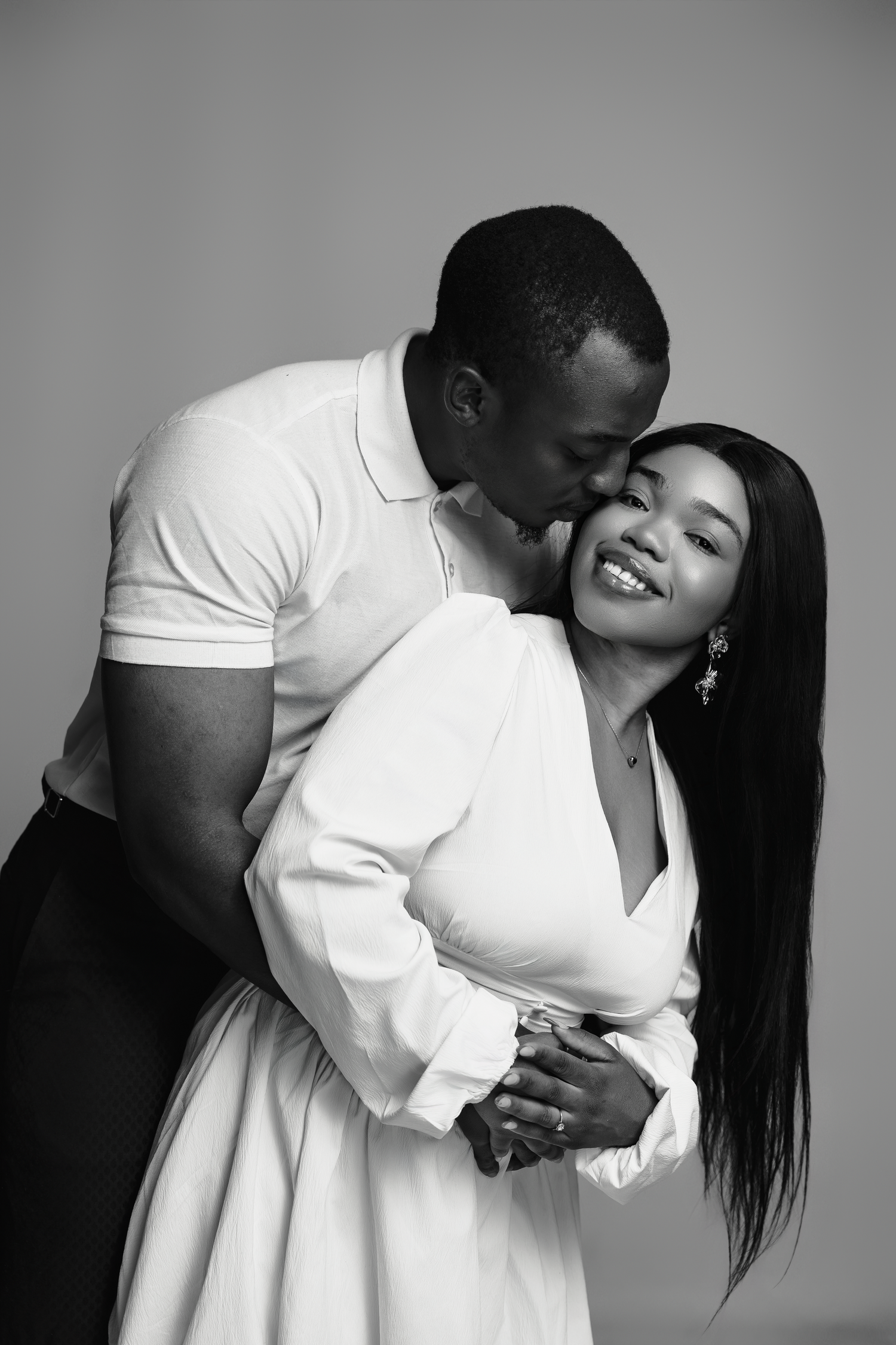 A romantic black and white photo series captures an intimate couple in white clothing embracing and sharing tender moments.