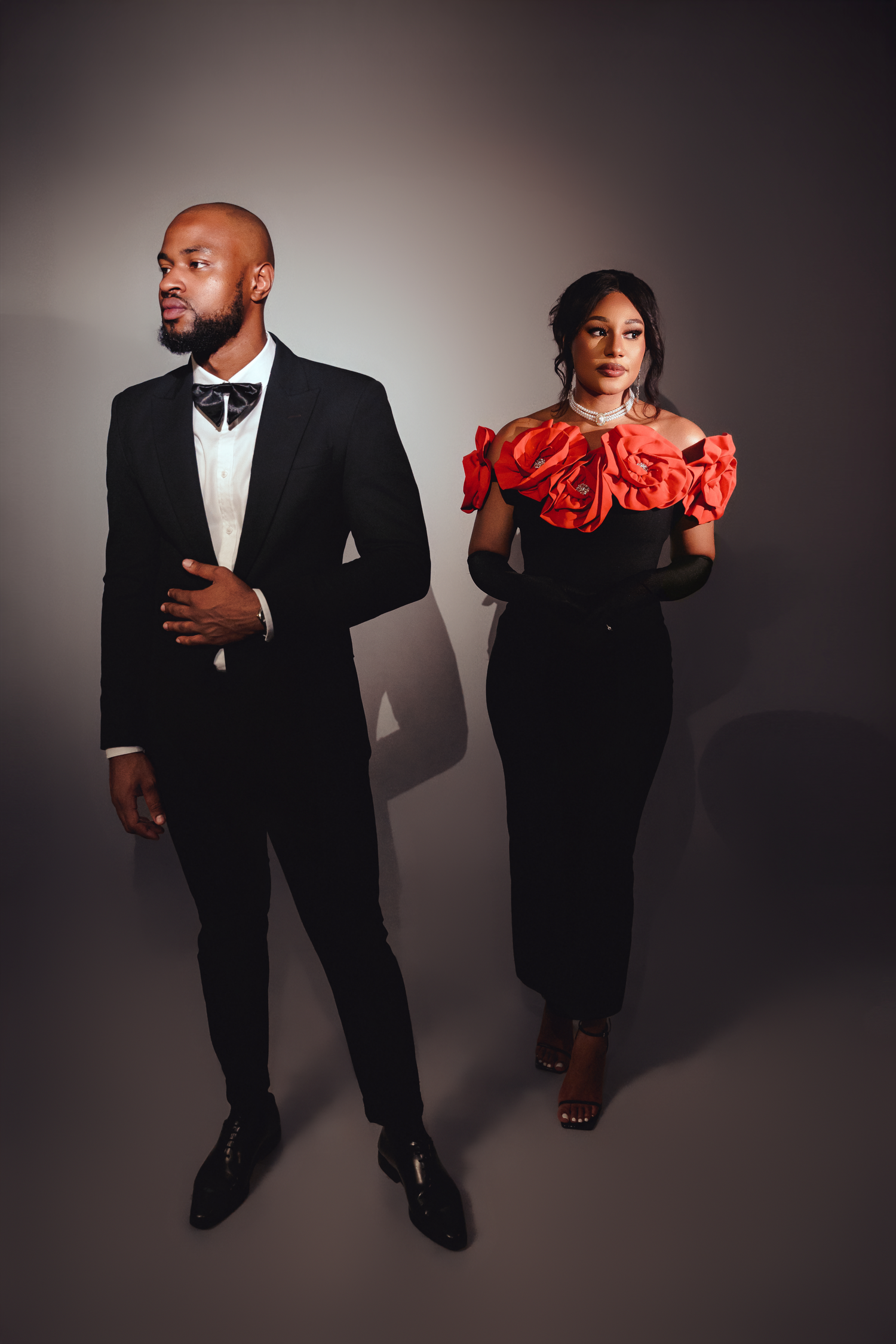 Dramatic fashion photoshoot with figures in black formal wear and red accents against dark background in sequential poses.