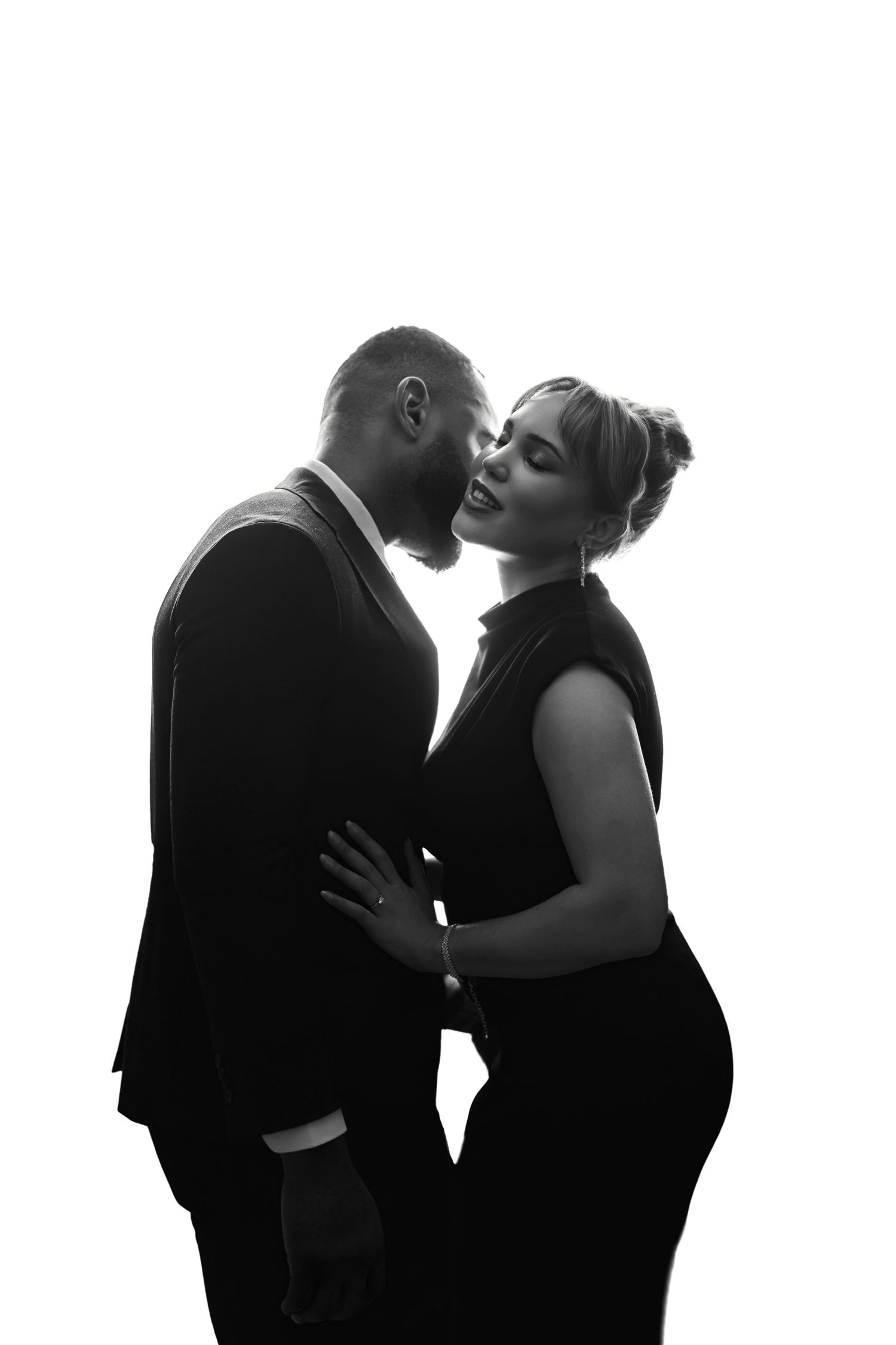 A romantic black and white silhouette of a couple in formal wear sharing an intimate moment.