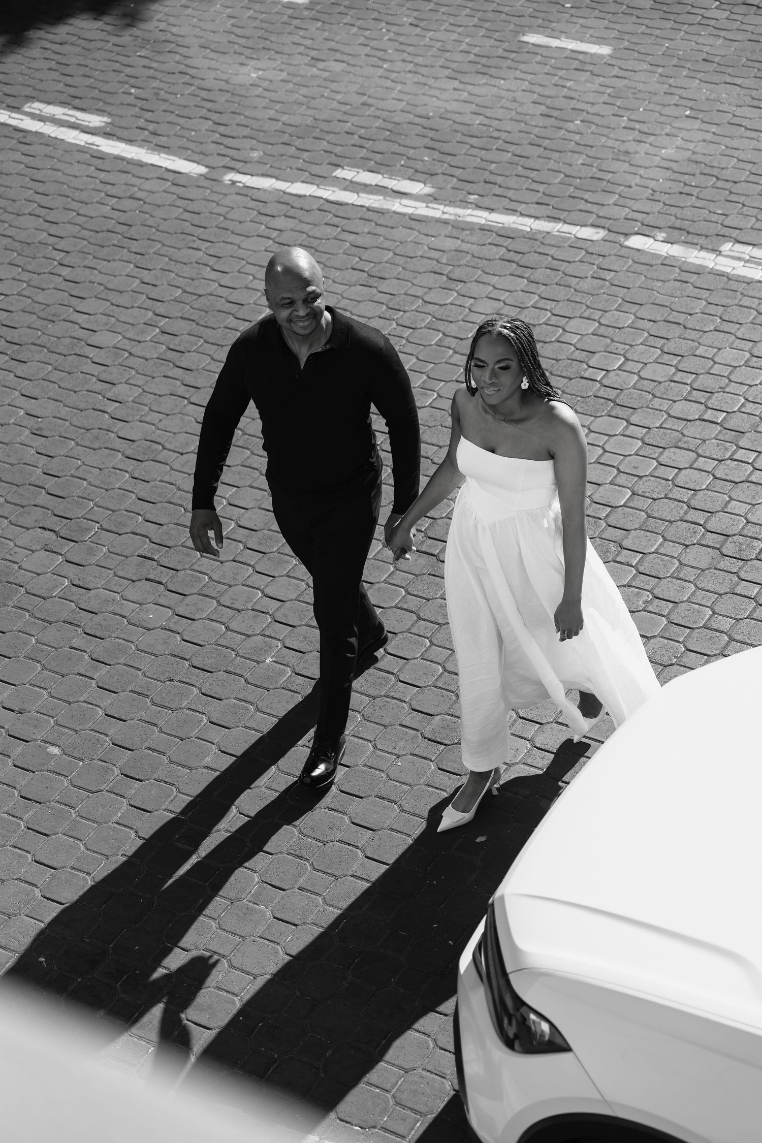 Black and white sequence showing a couple dancing on cobblestones, their shadows casting dramatic patterns on the ground.