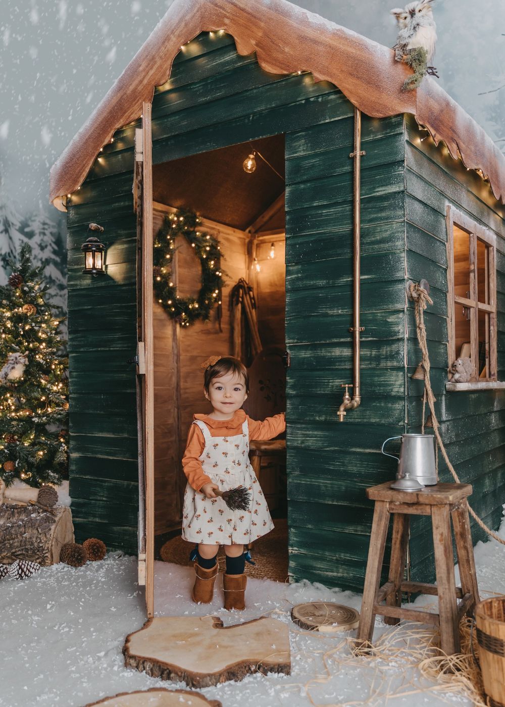 Cozy winter scene at a green cabin door with Christmas decorations and warm lighting.