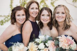 Bridal party holding pastel bouquets in navy and neutral dresses.