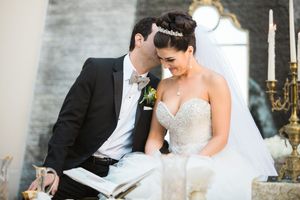 Couple shares intimate moment while signing documents at candlelit wedding ceremony.