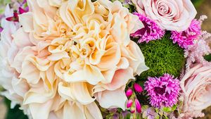 Close-up of peach and pink roses with green moss in a wedding bouquet arrangement.