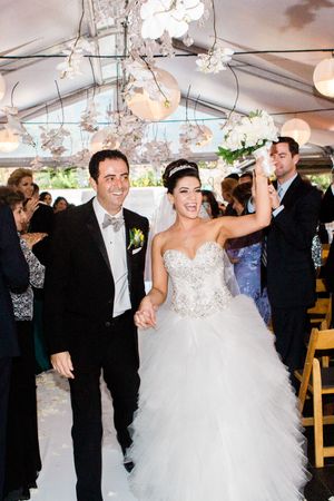 Newlyweds celebrate under crystal chandeliers at indoor reception venue.