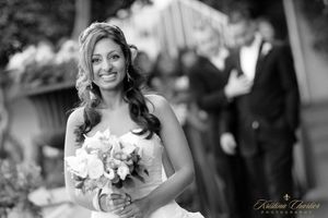 Black and white portrait of bride holding bouquet at outdoor wedding ceremony.