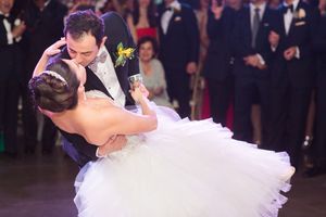 Couple performs romantic dip during their first dance at wedding reception.