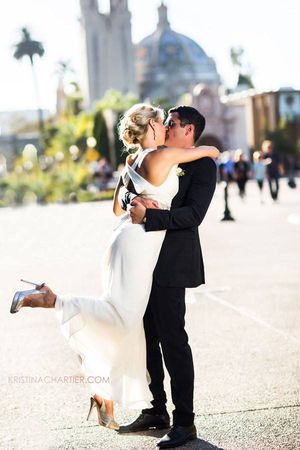 Romantic wedding photo in front of a grand domed building with palm trees.