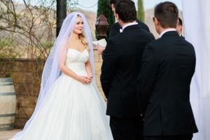 Wedding ceremony moment under white drapery with classic black and white attire.