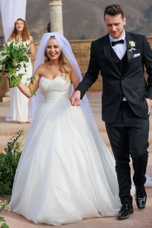Joyful wedding exit with white floral bouquet against mountain backdrop.