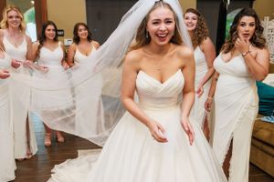 Joyful wedding scene with bridesmaids in white dresses celebrating behind the laughing bride.