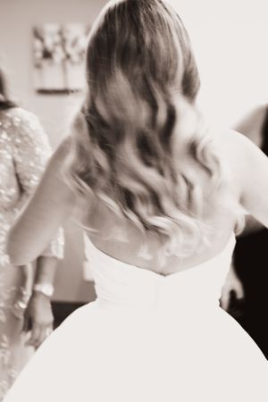 Black and white artistic photo of a bride's back showing her dress and flowing hair.