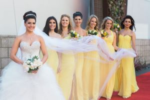 Bridal party poses together wearing yellow floor-length gowns and a white wedding dress.
