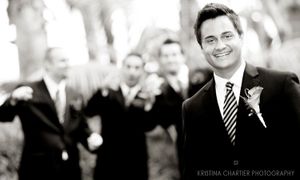 A candid black and white photo showing groomsmen at an outdoor wedding.