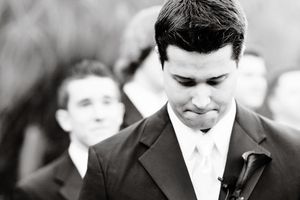 Black and white portrait of a groom in formal attire at a wedding ceremony.