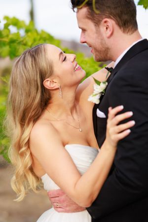 Romantic moment between newlyweds sharing a laugh in a garden setting.