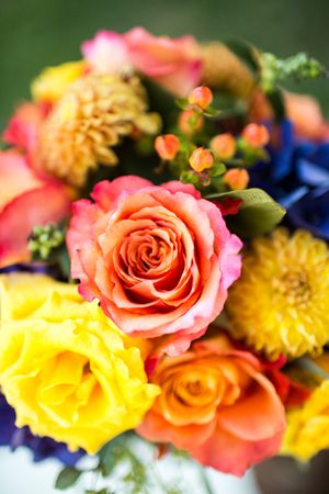 Vibrant wedding bouquet with coral, yellow and orange roses with colorful mixed flowers.