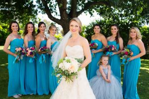 Wedding party portrait with bridesmaids in turquoise dresses and flower girl in light blue.