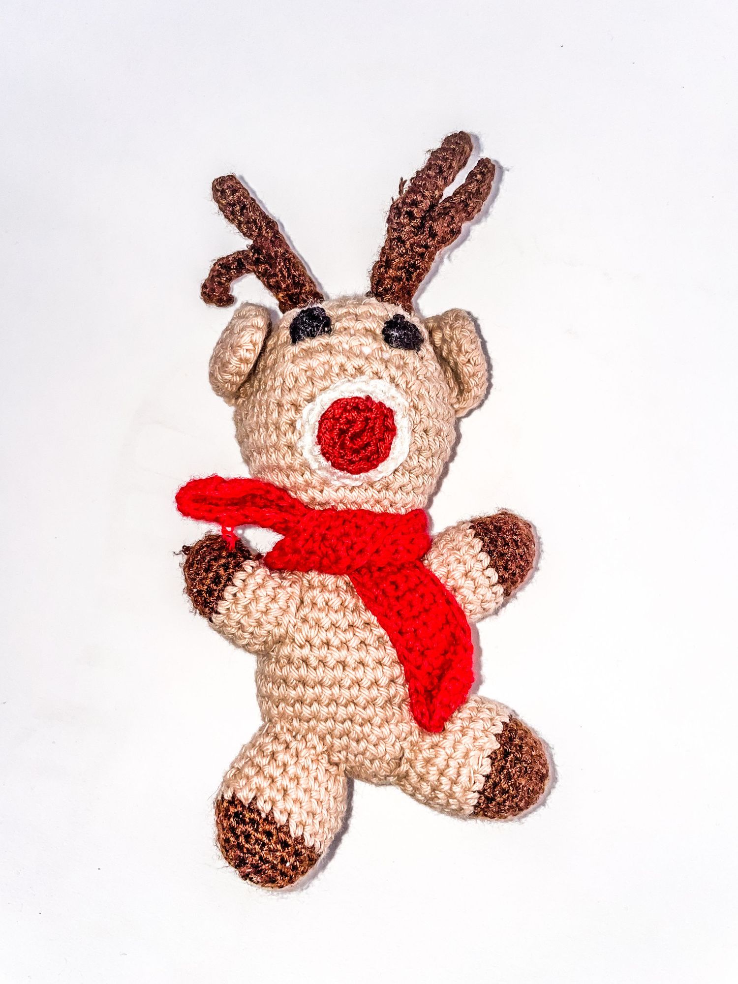 Crocheted reindeer plush toy with red nose and scarf for Christmas decor.
