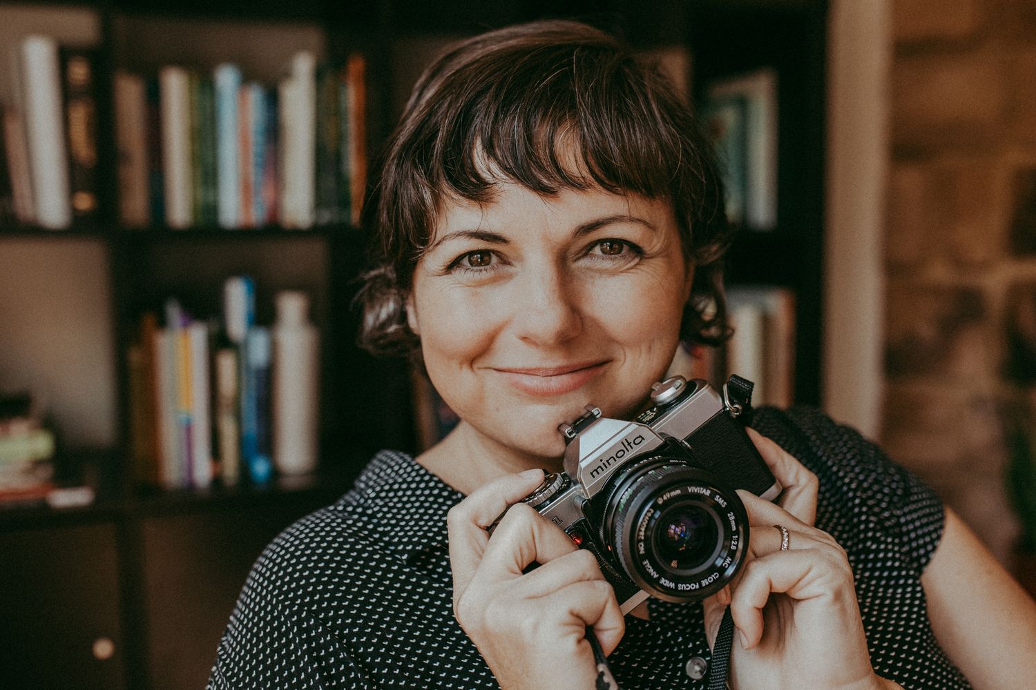 A series of six similar photos showing someone holding a camera in front of bookshelves in warm lighting. Whitney Popp, Arizona photographer