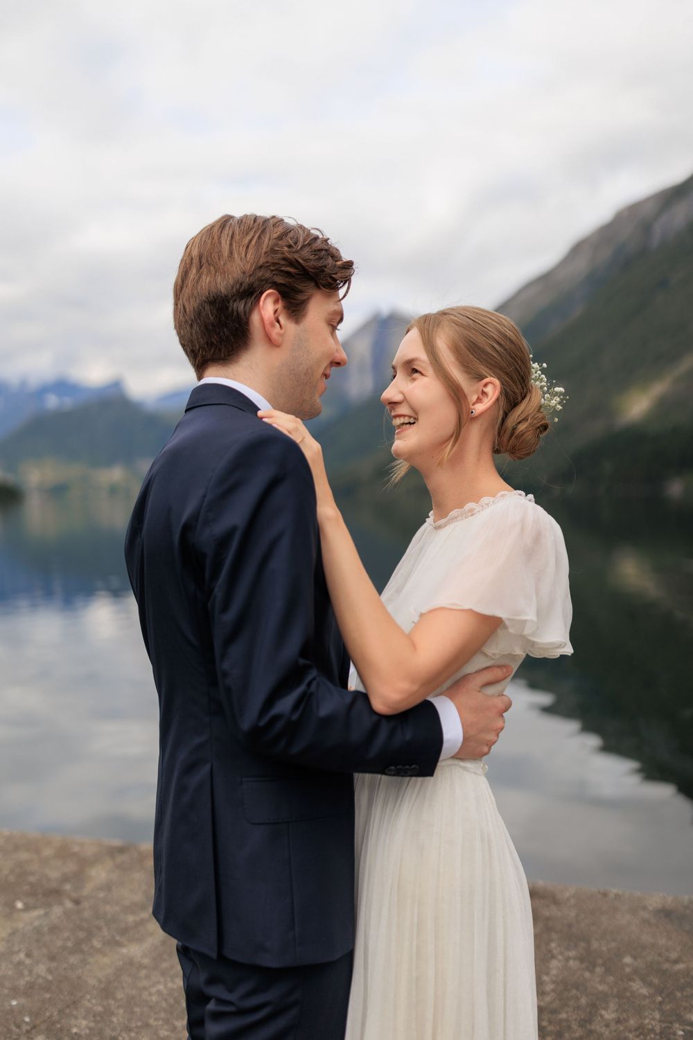 A romantic wedding moment captured by a mountain lake with dramatic cloudy skies.