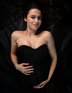 Classic black strapless evening gown against dark background.