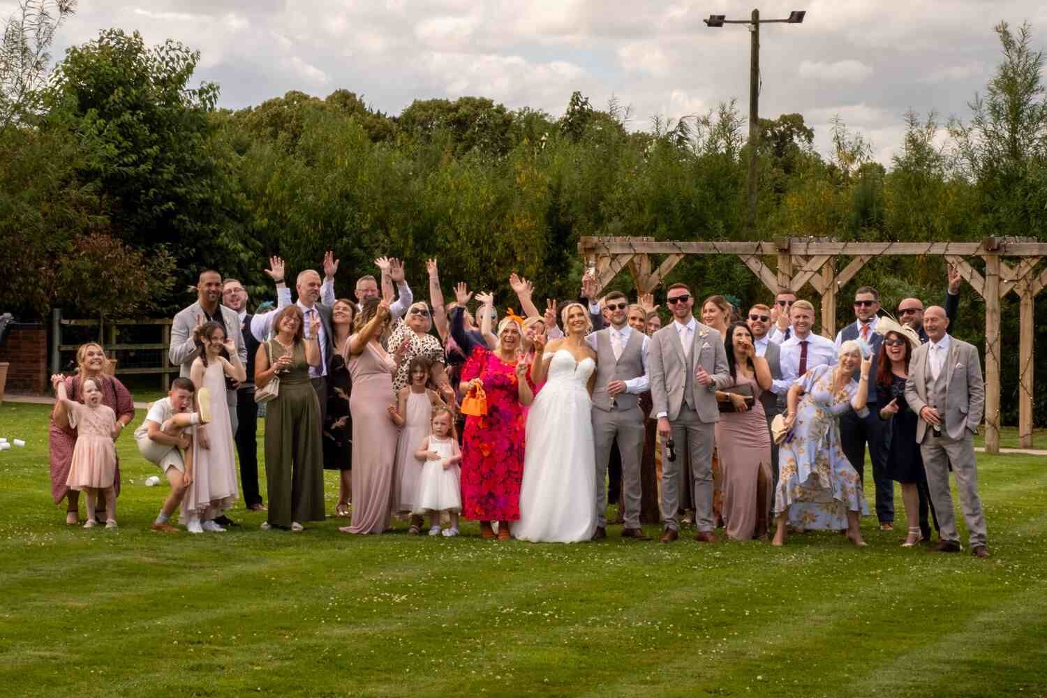 Large wedding group posing outdoors with the bride and groom.