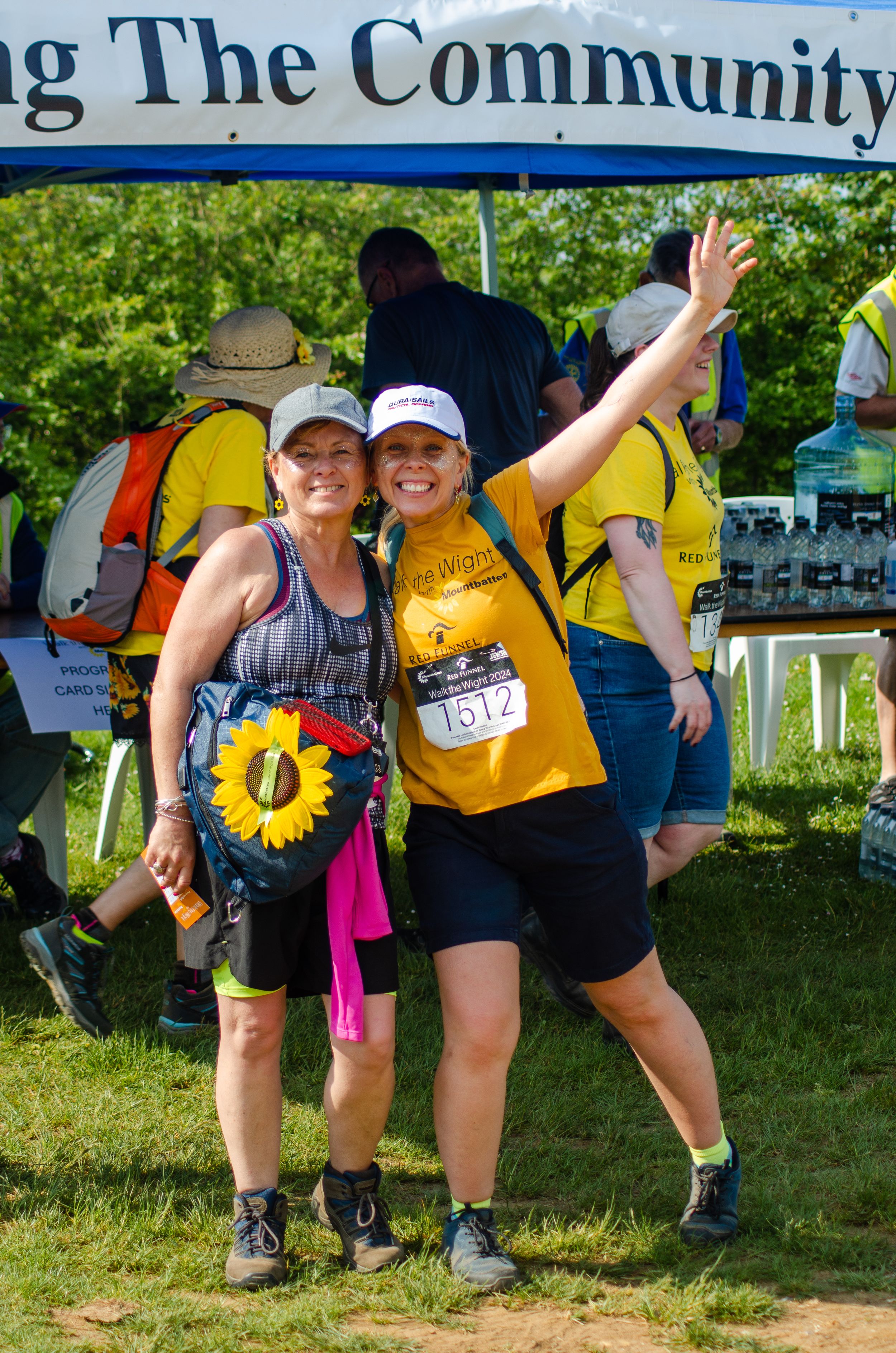 Participants wearing yellow shirts and sunflower accessories celebrate at community event finish line.