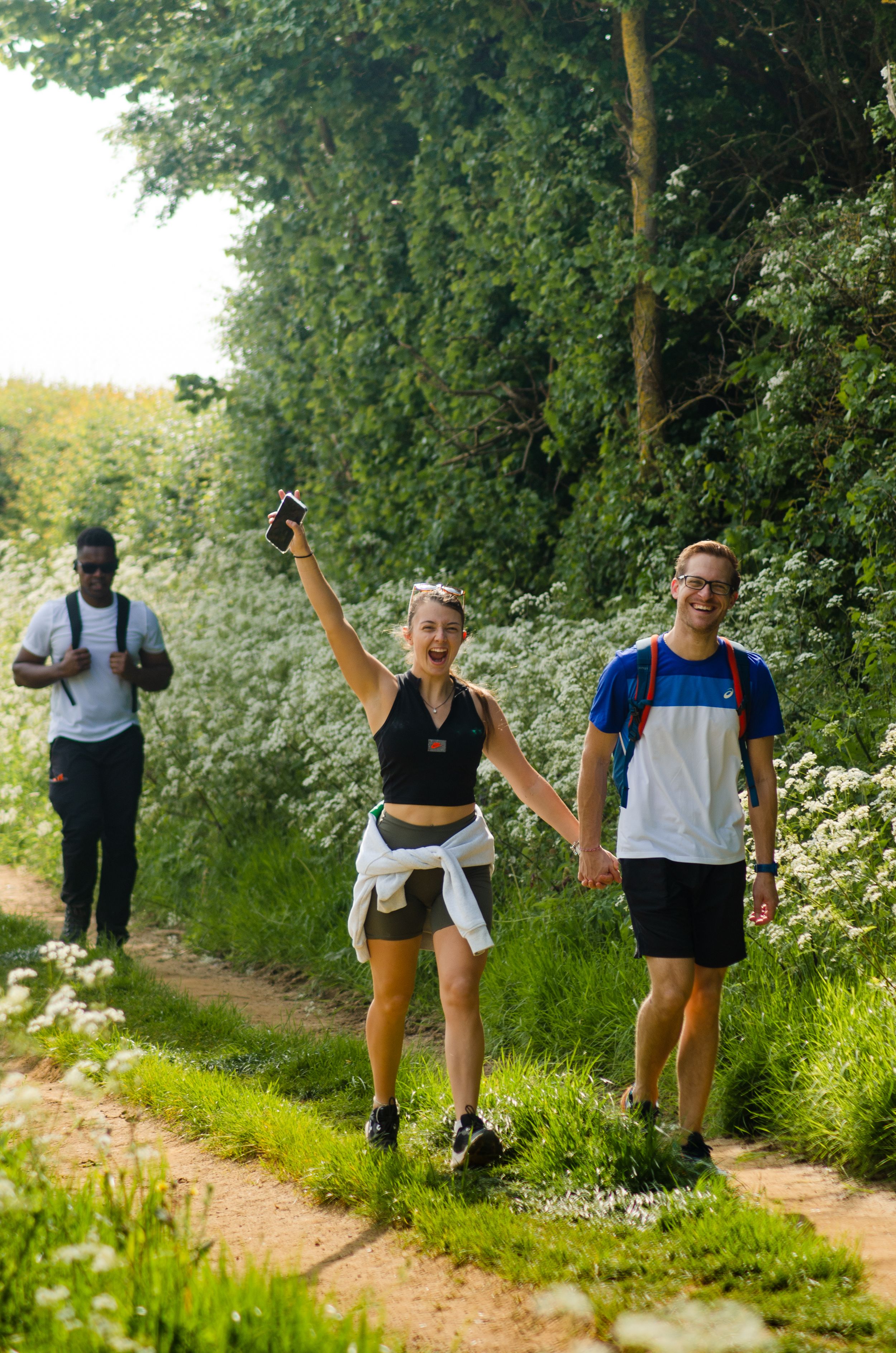 Enthusiastic hikers enjoying a sunny walk on a wildflower-lined trail.